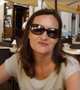 image of woman in sunglasses smiling tightly at the camera