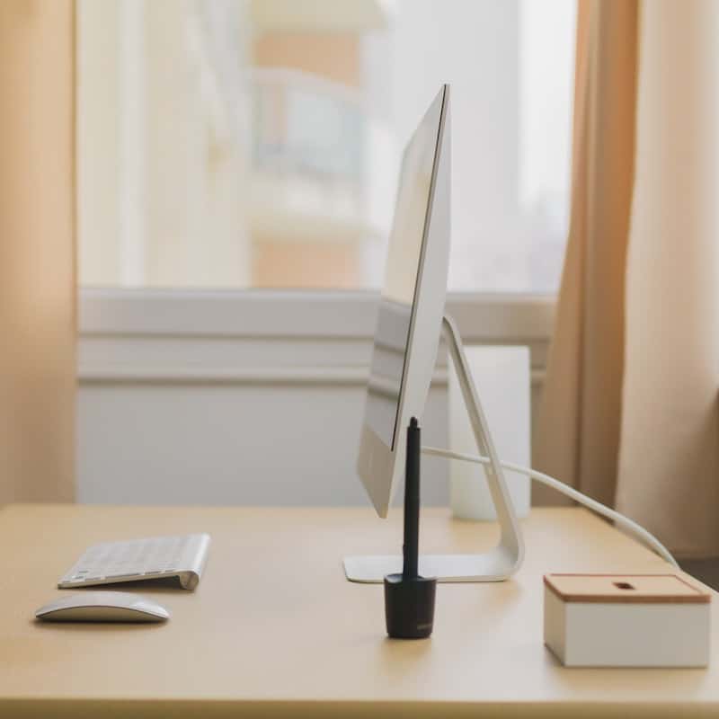 Computer on desk shown in stark profile with keyboard, mouse and digital pencil